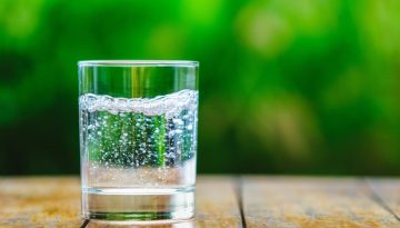 A,Glass,Of,Water,On,Green,Background.,The,Wooden,Table.